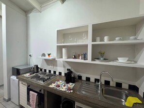A modern kitchen with a gas stove, a sink, and white shelves above. - Experience Elevated Living in Dainfern's Panorama Suite (Johannesburg)