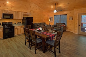 A cabin interior with a dining area, kitchen, and seating space. - Hideaway Haven | Hot Tub, Game Room, Resort Pool, Fireplace + Free Attraction Tickets (Sevierville)