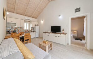 Ein kompakter Wohnbereich mit Küchenzeile, Essbereich, Sofa und Fernseher.