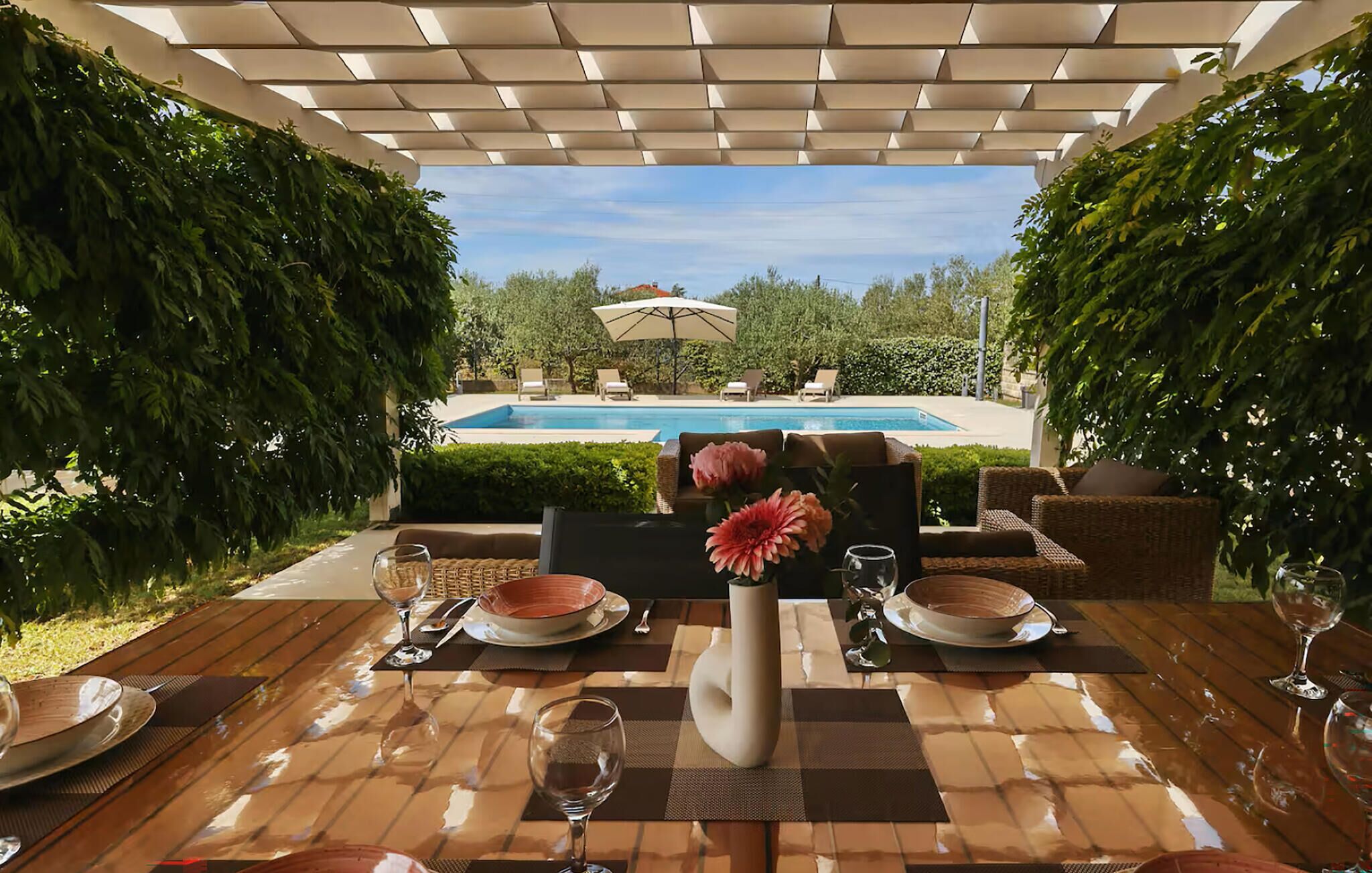 An outdoor dining area with a pool in the background.