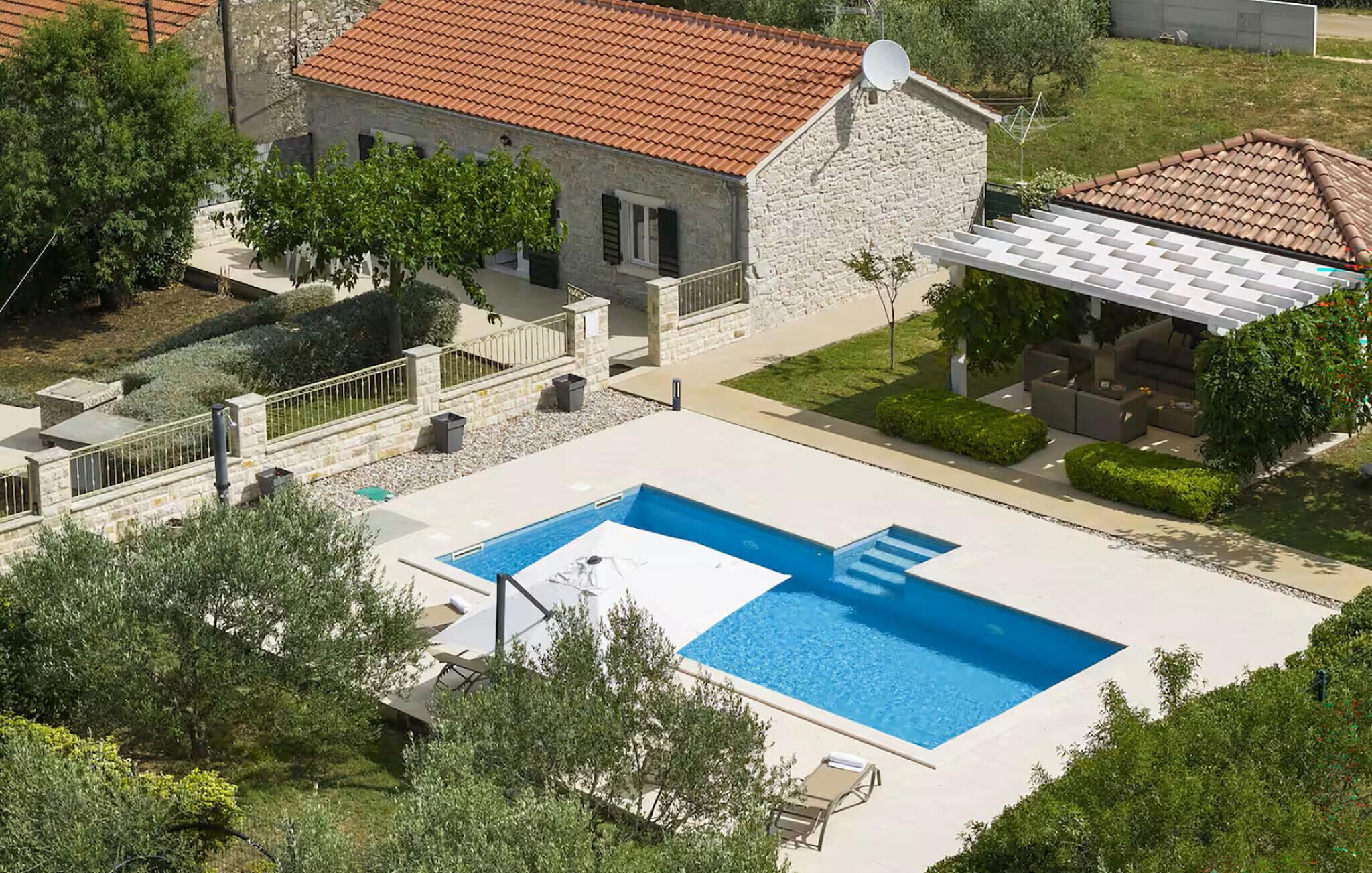 Une propriété résidentielle dotée d’une piscine, d’une maison en pierre et d’un espace extérieur aménagé pour se détendre.