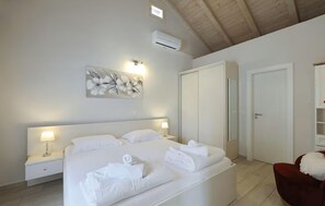 A hotel room with a bed, bedside lamps, a wall-mounted air conditioner, a wardrobe, and a mirror. - Nice home in Debeljak with private swimming pool, can be inside or outside (Debeljak)