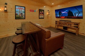 A cozy room with a wooden interior, a bar area, and a large flat-screen TV mounted on the wall. - A Smoky Mountain Dream | Mountain Views | Private Pool | Hot Tub (Wears Valley)