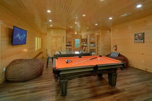A pool table in a wooden room with a fireplace, a television, and a game room sign. - A Smoky Mountain Dream | Mountain Views | Private Pool | Hot Tub (Wears Valley)