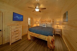 A wooden cabin bedroom with a bed, dresser, nightstands, and a ceiling fan. - A Smoky Mountain Dream | Mountain Views | Private Pool | Hot Tub (Wears Valley)