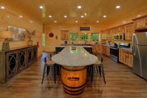 A kitchen with wooden cabinets, a granite countertop island, and modern appliances. - A Smoky Mountain Dream | Mountain Views | Private Pool | Hot Tub (Wears Valley)