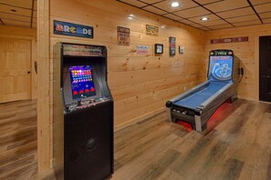A room with wooden walls, a pool table, and a video game machine. - A Mountain Paradise | Theater Room | Game Room | Hot Tub (Pigeon Forge)