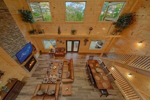 A spacious interior with a fireplace, leather sofas, a dining table, and multiple windows. - A Mountain Paradise | Theater Room | Game Room | Hot Tub (Pigeon Forge)