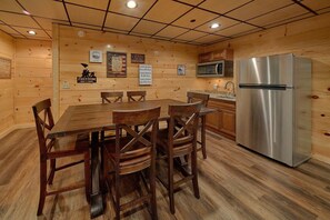 A wooden interior with a dining table, chairs, a stainless steel refrigerator, and a microwave. - A Mountain Paradise | Theater Room | Game Room | Hot Tub (Pigeon Forge)