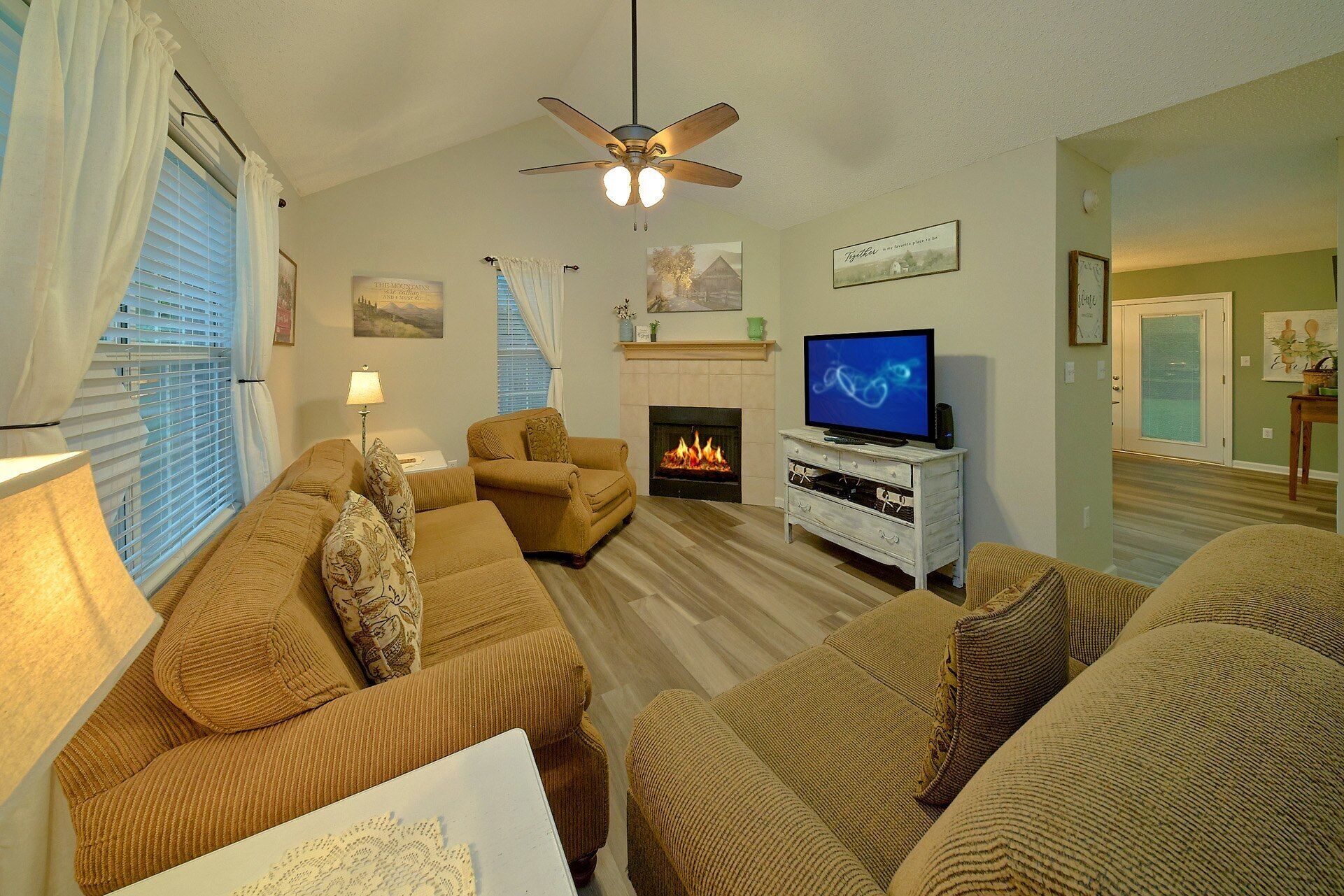 A living room with a fireplace, a television, and a ceiling fan.