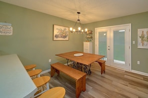 A dining area with a wooden table, benches, and a chandelier. - Mill Creek Cottage | Hot Tub, Pigeon Forge, Fireplace + Free Attraction Tickets (Pigeon Forge)