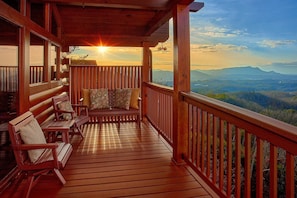 A wooden deck with a bench and chairs, overlooking a mountainous landscape. - Chocolate Moose | Mountain Views | Hot Tub | Pool Table (Sevierville)