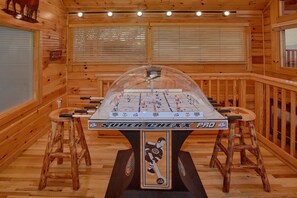 A foosball table with a hockey theme, surrounded by wooden walls and a window with blinds. - Chocolate Moose | Mountain Views | Hot Tub | Pool Table (Sevierville)