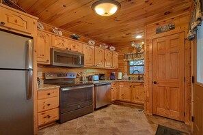 A wooden cabin-style kitchen with a refrigerator, microwave, stove, and dishwasher. - Chocolate Moose | Mountain Views | Hot Tub | Pool Table (Sevierville)