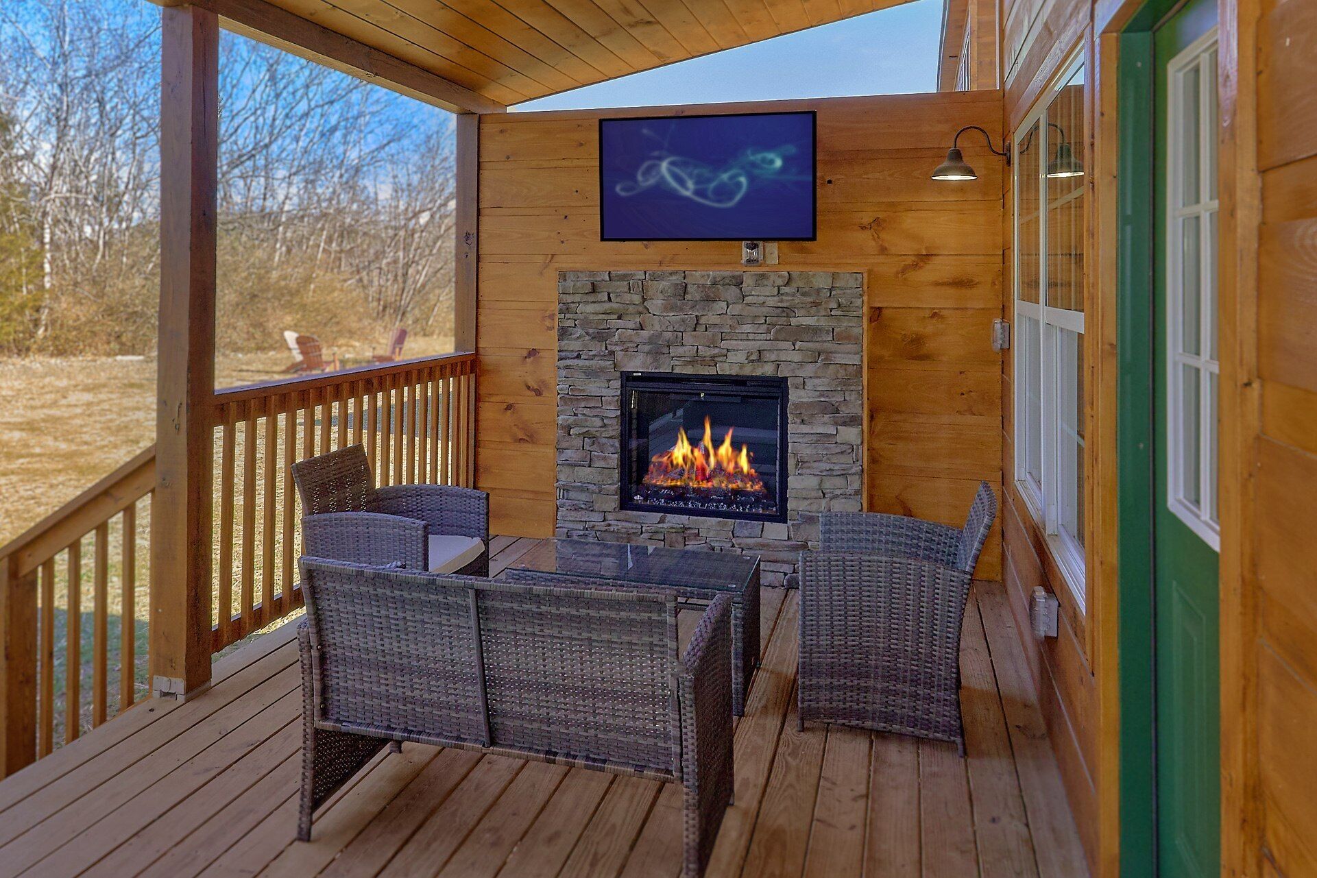 A wooden deck with wicker furniture and a stone fireplace.