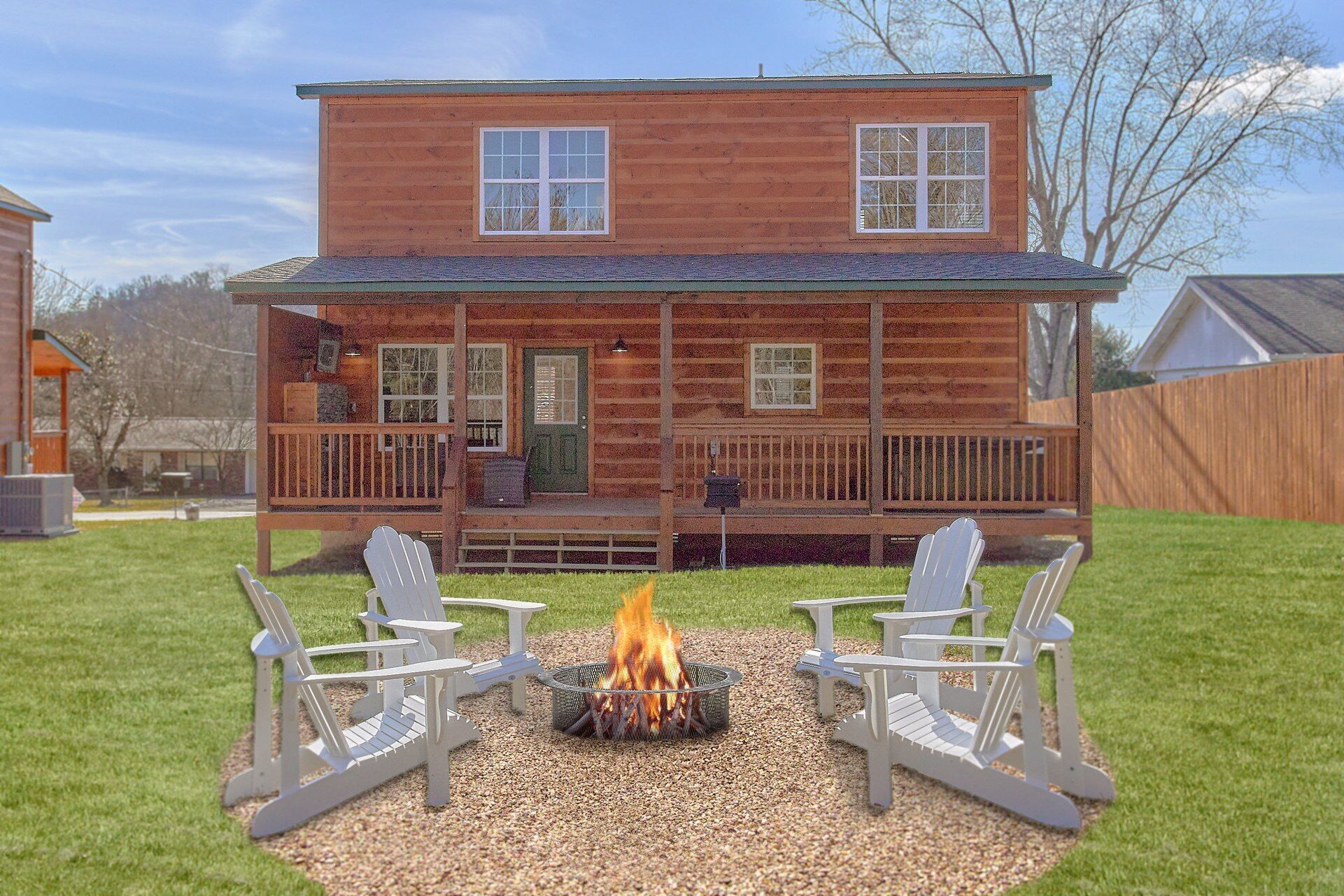 Eine zweistöckige Blockhütte mit Veranda, Feuerstelle und zwei Adirondack-Stühlen.