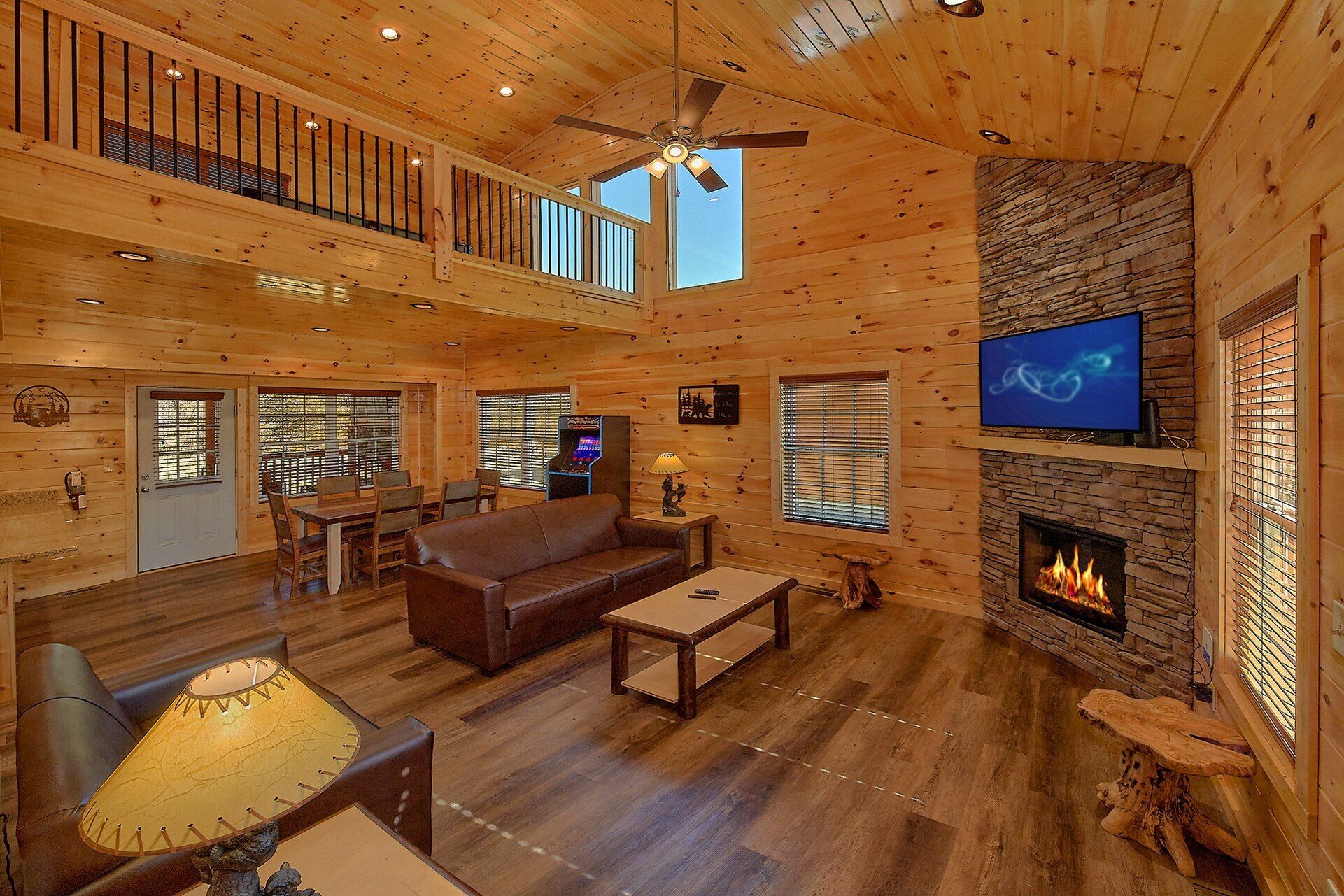 A spacious log cabin interior with a fireplace, a television, and a dining area.