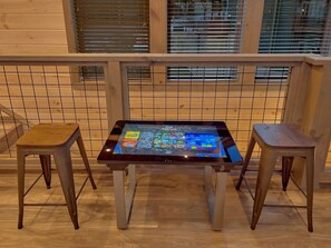 Une table dotée d’une interface numérique, dans une pièce au plancher en bois et munie d’une rambarde en métal.