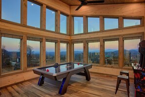 Ein Zimmer mit Billardtisch, großen Fenstern und Bergblick.
