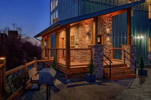 A modern building with a stone facade, large windows, and a wooden deck. - Gatlinburg Splash | Private Pool, Mtn Views, Hot Tub, Game Room, Fireplace + Free Attraction Tickets (Gatlinburg)