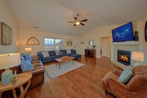 A spacious living room with a fireplace, a ceiling fan, and a television. - Bear Necessities Vacation Home (Sevierville)