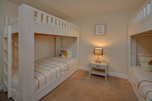 A room with bunk beds, a bedside table with a lamp, and a wall decoration. - Bear Necessities Vacation Home (Sevierville)