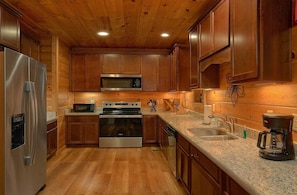 A kitchen with wooden cabinets, stainless steel appliances, a granite countertop, and a wooden ceiling. - Smoky Vista Lodge | Theater, Mtn Views, Hot Tub, Game Room, Sleeps 10 + Free Attraction Tickets (Gatlinburg)