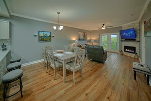 A spacious living area with a dining table, chairs, a sofa, a fireplace, and a television. - Mountain View 2504 | Mtn Views, Pigeon Forge, Resort Pool, Fireplace + Free Attraction Tickets (Pigeon Forge)