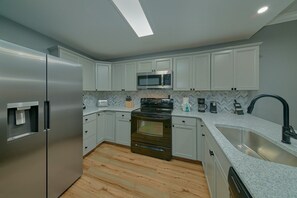 A modern kitchen with a stainless steel refrigerator, a microwave, an oven, and a sink. - Mountain View 2504 Condo Suite (Pigeon Forge)