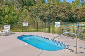 A swimming pool with a metal fence, lounge chairs, and warning signs. - Mountain View 2504 Condo Suite (Pigeon Forge)