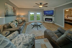 A living room with a fireplace, a television, and a ceiling fan. - Mountain View 2504 | Mtn Views, Pigeon Forge, Resort Pool, Fireplace + Free Attraction Tickets (Pigeon Forge)