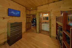 A wooden interior with a television, a desk, a chair, a sink, and a bed. - Above Walden's Creek | Game Room | Hot Tub (Pigeon Forge)