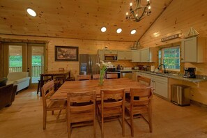 A wooden interior with a dining table, chairs, a refrigerator, a microwave, and a kitchen counter. - Above Walden's Creek | Game Room | Hot Tub (Pigeon Forge)
