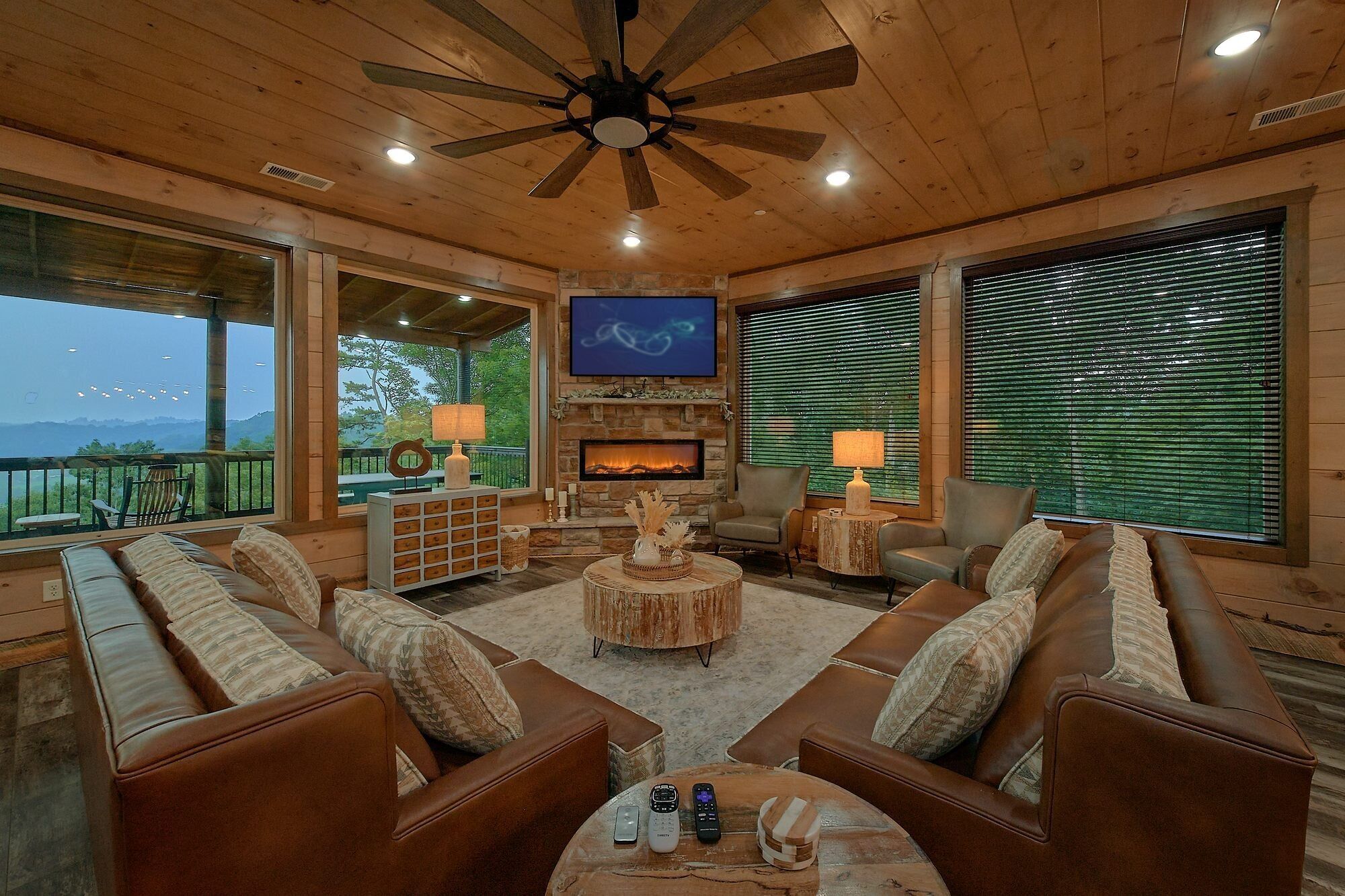 A spacious living room with leather sofas, a fireplace, and a television.
