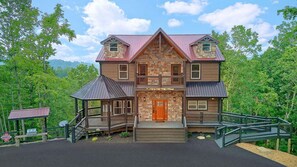 A two-story lodge with a stone facade, a wooden porch, and a metal roof. - A View From Above | Private Pool | Hot Tub | Mountain Views (Sevierville)