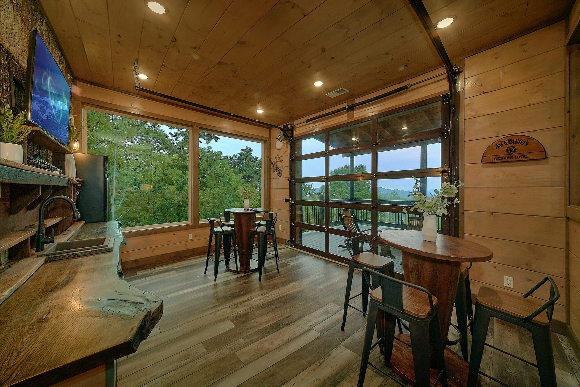 A wooden interior with a bar area, large windows, and a view of greenery.
