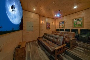 A cozy room with a large couch, a wooden floor, and a wall with a poster. - A View From Above | Private Pool | Hot Tub | Mountain Views (Sevierville)