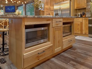 A kitchen with wooden cabinetry, stainless steel appliances, and a granite countertop. - A View From Above | Private Pool | Hot Tub | Mountain Views (Sevierville)