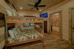 Ein Schlafraum mit Etagenbetten, Deckenventilator, Holzwänden und einem Fenster mit Jalousien.