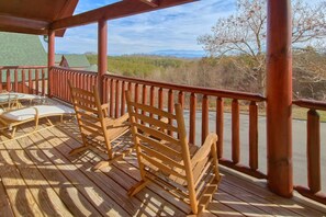 Eine Holzterrasse mit Sitzgelegenheiten und Blick auf eine gebirgige Landschaft.