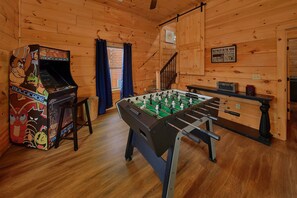 Ein Zimmer mit Holzwänden und Holzböden, einem Kicker und einer Spielkonsole.