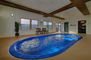 Una piscina interior con techo de madera, ventanas amplias y un cartel para toallas de piscina.