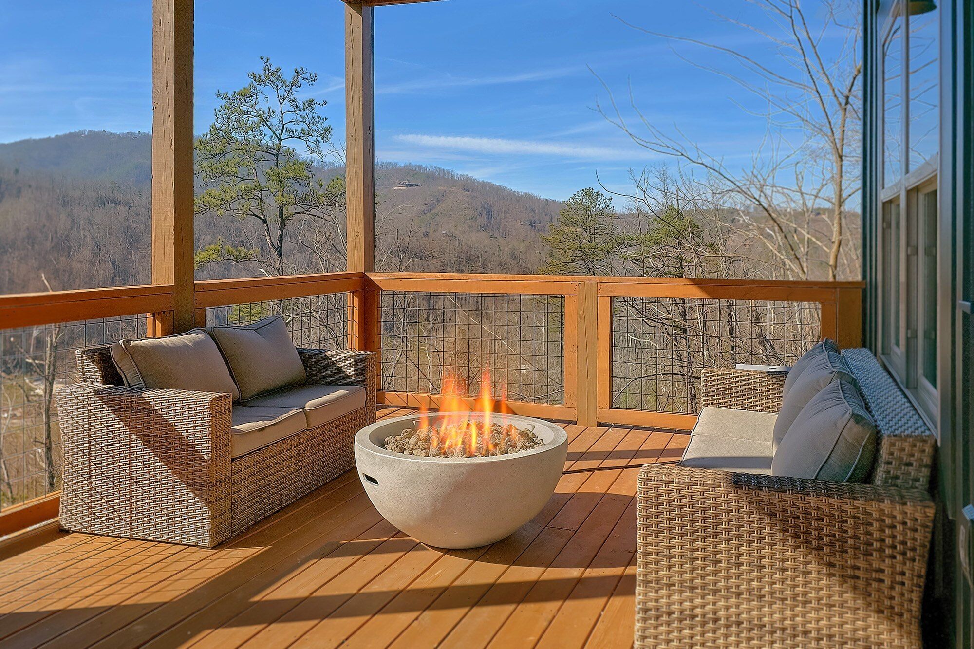 Eine Holzterrasse mit Feuerstelle und Korbmöbeln.