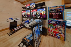 Una sala de juegos con múltiples pantallas mostrando distintos juegos, incluyendo 'Time Crisis 5' y 'Donkey Kong'.