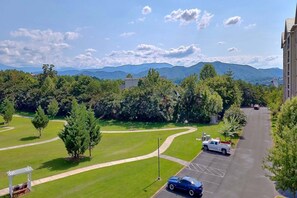 A parking area with a blue car, a white truck, and a paved road leading to a building. - Mountain View 3206 | Pigeon Forge, Resort Pool, Fireplace + Free Attraction Tickets (Pigeon Forge)