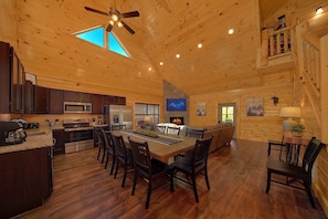A spacious wooden interior with a dining area, kitchen, and a fireplace. - Swimming in the Smokies | Indoor Pool, Hot Tub, Game Room, Sleeps 12 + Free Attraction Tickets (Pigeon Forge)