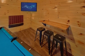 A sauna room with wooden walls, a television mounted on the wall, and three stools. - Swimming in the Smokies | Indoor Pool, Hot Tub, Game Room, Sleeps 12 + Free Attraction Tickets (Pigeon Forge)
