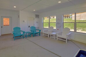 A room with two sets of Adirondack chairs, a door, and a window with a view of a grassy area. - Swimming in the Smokies | Indoor Pool, Hot Tub, Game Room, Sleeps 12 + Free Attraction Tickets (Pigeon Forge)