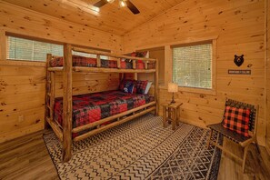 A cabin with a bunk bed, a small table with a lamp, and a sign on the wall. - Misty Shadows Splash | Private Pool, Hot Tub, Game Room, Fireplace + Free Attraction Tickets (Wears Valley)