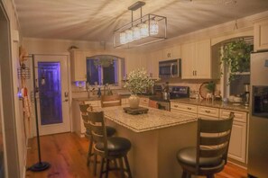 A kitchen with a central island, wooden chairs, a microwave, and a refrigerator.